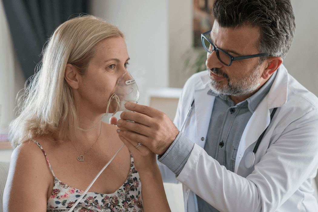 Young male doctor assisting his woman patient with a breathing treatment.