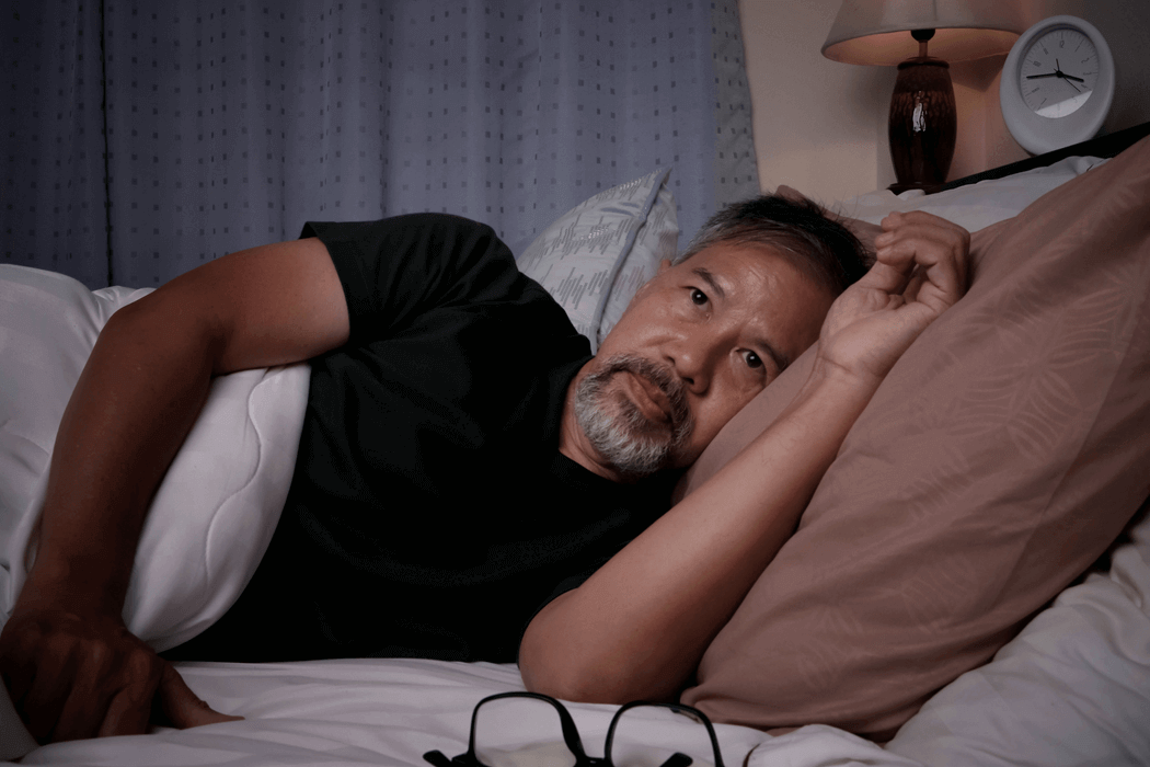Man laying in bed with eyes wide open as if he cannot sleep