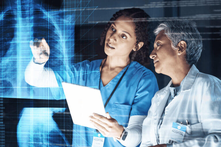 Young woman doctor in a dark room reading an x-ray on the wall in front of her.