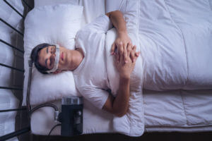 A man with sleep apnea is wearing a CPAP mask and sleeping soundly in bed all night without snoring.
