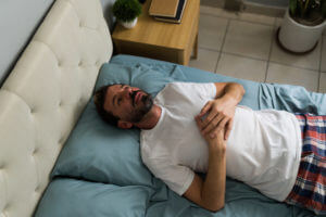 A man lying in bed and experiencing shortness of breath.