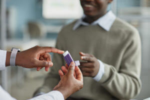 Young Adult Black Man Receiving Asthma Inhaler from An Asthma Doctor.